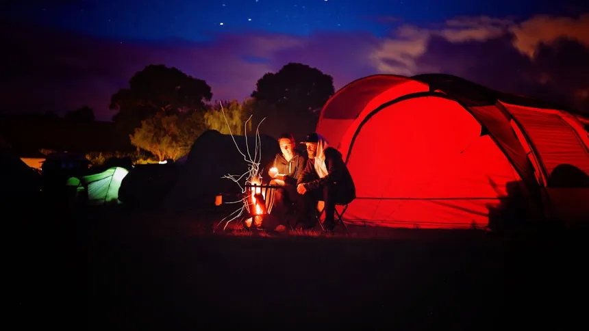 Camping scene at night with illuminated tent showing outdoor setting where portable power stations are commonly used