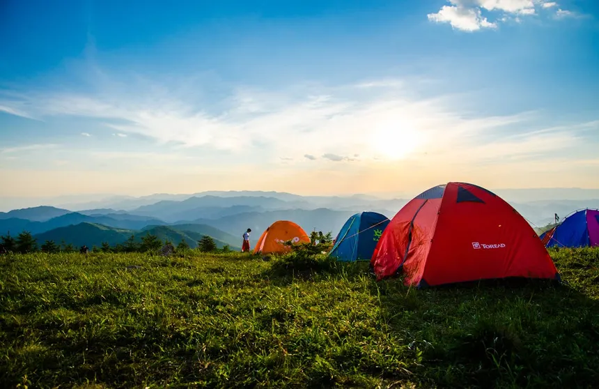 Colorful camping tents set up on a mountain ridge at sunset, illustrating outdoor adventures where portable power is essential