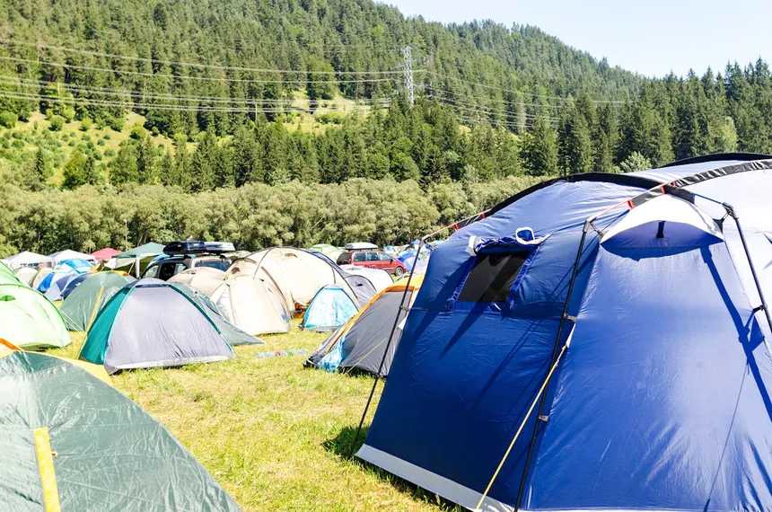 Outdoor camping scene with colorful tents in a mountainous campground, showing where portable power stations are commonly used