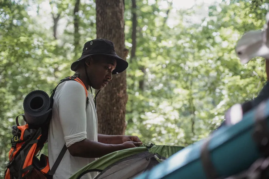 Camper setting up tent in forest for outdoor adventure with portable power station