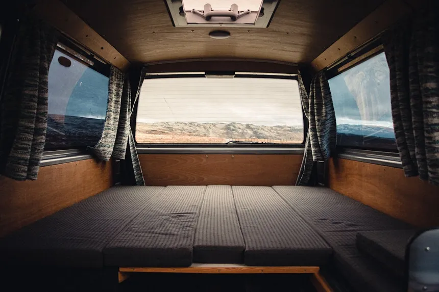 Camper van interior with bed and wooden panels - the van life lifestyle where portable power stations shine